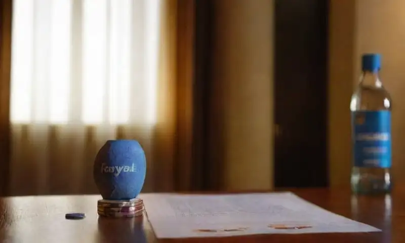 Una habitación tenue muestra una pantalla de PayPal y un sitio de apuestas, con un teléfono, fichas de colores, y un ambiente cálido que sugiere una atmósfera de apuestas seguras