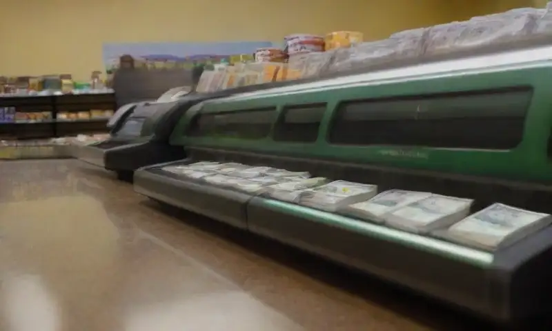 Una caja registradora de Walmart con billetes ordenados y un ambiente vibrante de compras